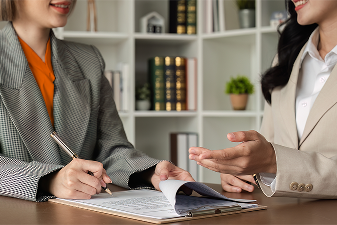 Two female paralegal coworkers discussing documents on a clipboard